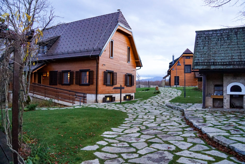 A flagstone path leads to the large, two story wood cabins, with steep rooflines