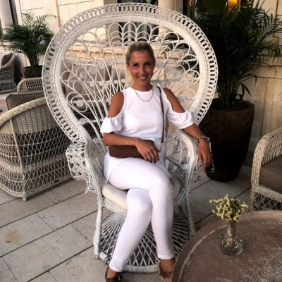 Our concierge Mirela dressed in all white, sitting on a large oversized wicker chair on the terrace