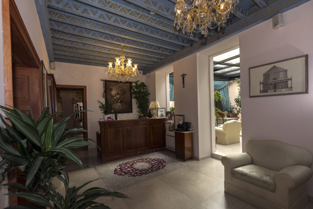 Reception area large tile floors, under painted wood beamed roof, finished with two chandeliers. 