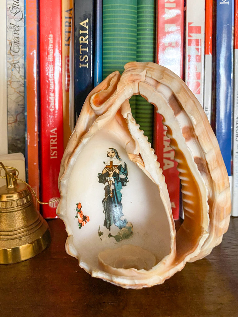 A conch shell cut in half with Santa Teresa Delle Rose painted on it - a childhood souvenir cherished by Wanda S. Radetti of Tasteful Croatian Journeys. 